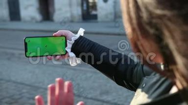 女孩在智能手机上说话，手机的绿色屏幕。 向屏幕上看到的人挥手